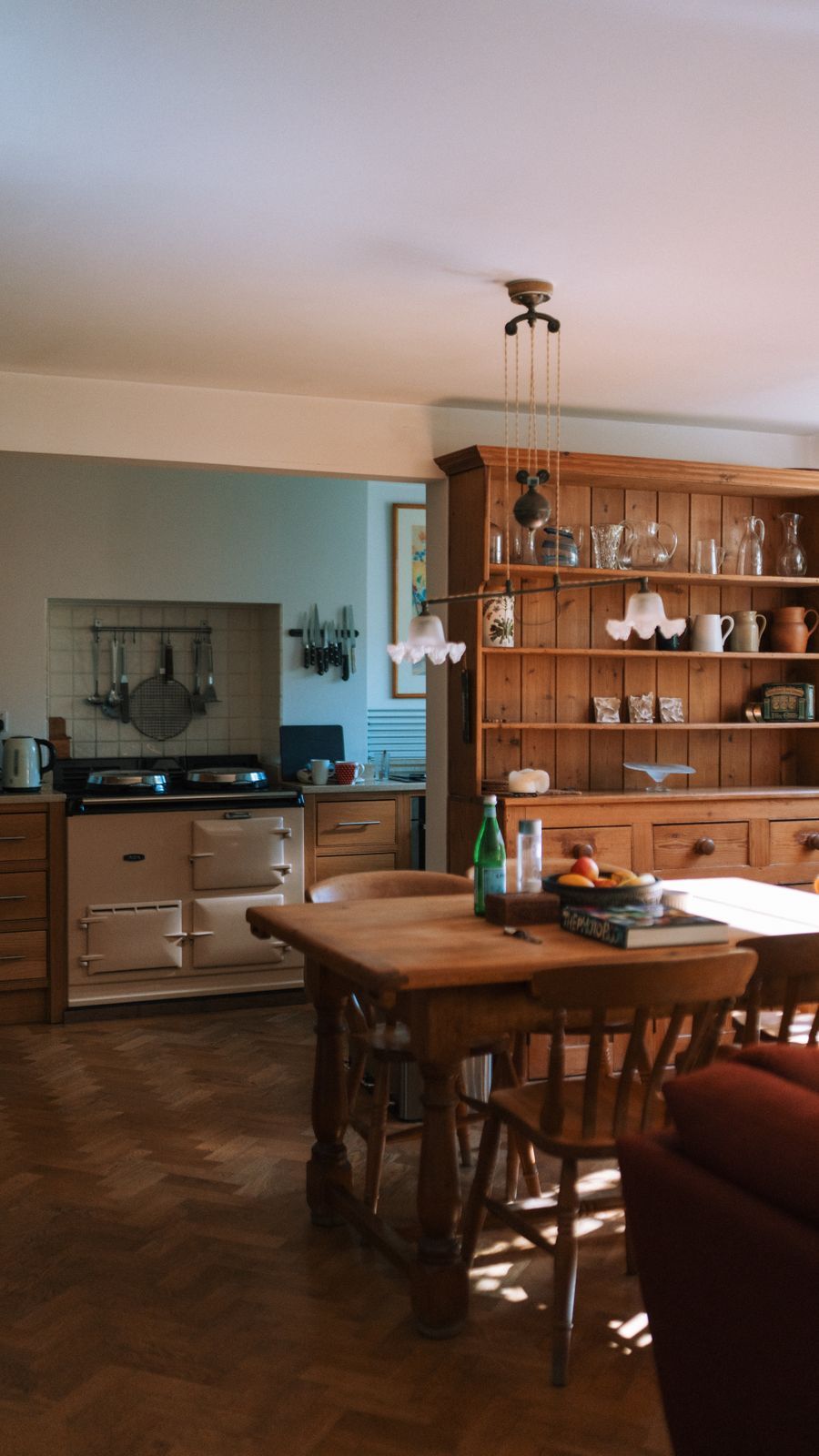 A cream two-oven AGA in a farmhouse kitchen, with a pine dresser and dining table